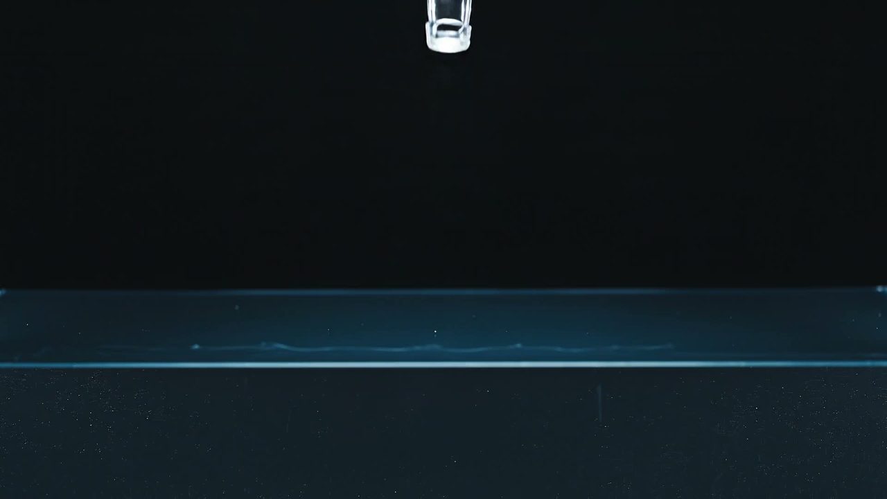 Botella de vidrio cayendo en agua purificada